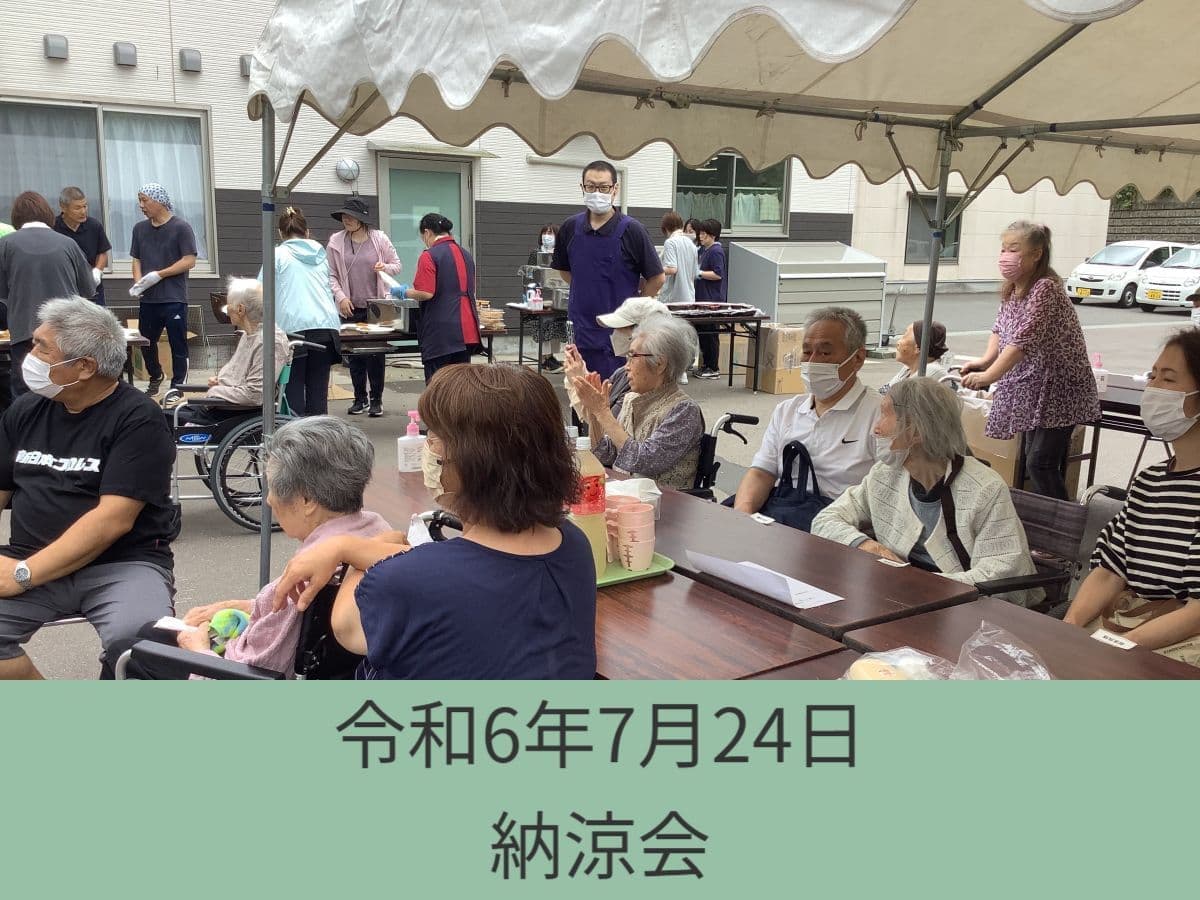 施設の納涼会。テント下でテーブルに着座した高齢入居者と職員が集まり、イベントを楽しんでいる。